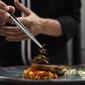 Semut bersayap dihidangkan di atas hidangan fillet ikan di dapur restoran Insects in the Backyard, Bangkok, 15 Agustus 2017. Restoran kelas atas ini menjadi yang pertama membuka menu hidangan makanan dengan kombinasi serangga. (LILLIAN SUWANRUMPHA/AFP)