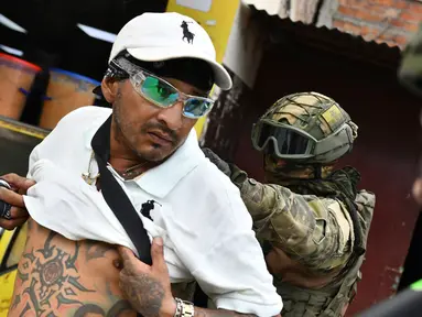 Tentara memeriksa punggung seorang pria untuk memeriksa tato geng selama operasi penghentian dan penggeledahan di Portoviejo, Ekuador, Kamis (11/1/2024). Presiden Ekuador Daniel Noboa pada Senin menetapkan keadaan darurat nasional karena gelombang kejahatan, sebuah tindakan yang memungkinkan pihak berwenang menangguhkan hak-hak masyarakat dan memobilisasi militer. (AP Photo/Ariel Ochoa)