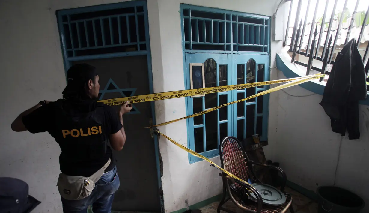Petugas memasang garis polisi di sebuah rumah seusai penggerebekan peredaran narkoba di kawasan Kampung Ambon, Cengkarang, Jakarta, Rabu (24/1). Dalam penggrebekan, dikerahkan sekitar 150 personel gabungan dari Brimob dan TNI. (Liputan6.com/Arya Manggala)