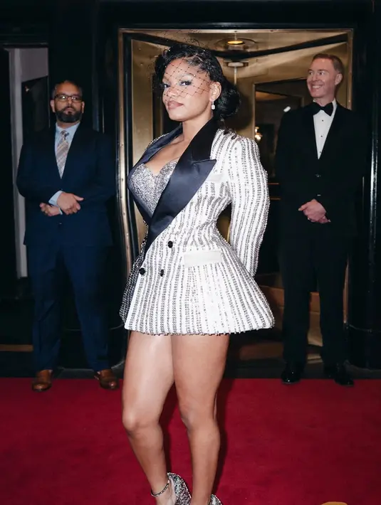 Halle Bailey mengenakan Coach tampilan yang terinspirasi dari Harlem Renaissance yang menampilkan jaket malam bergaris-garis berkerah tinggi dari wol biru tua dan krem ​​yang dibuat oleh @arturocastaneda_. Pakaian tersebut dihias dengan cermat dengan lebih dari 10.000 kristal pavé berwarna senada. Halle juga mengenakan sepatu hak platform berhias dengan kristal pavé dan kerudung penyaring yang dapat menyebar dengan berlian imitasi denim. [Coach]