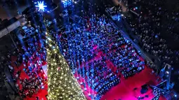 Warga mengikuti peresmian menyalakan lampu pohon natal di Beirut, Lebanon (10/12). Menyambut datangnya natal, warga Beirut merayakan peresmian pohon natal yang dipajang bersebelahan dengan Masjid Mohammad al-Amin. (AFP Photo/Stringer)