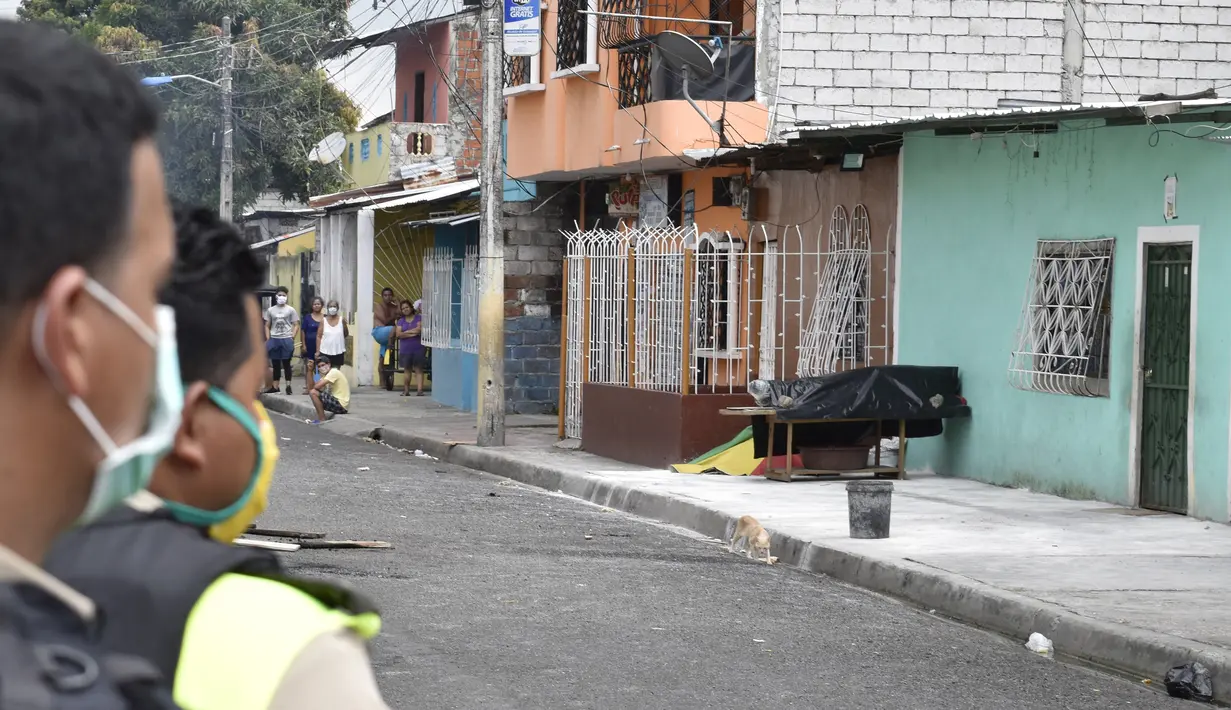 Polisi melihat ke arah jenazah yang diduga meninggal karena virus corona COVID-19 di teras sebuah rumah di pinggiran Guayaquil, Ekuador, Jumat (3/4/2020). Hingga 6 April 2020, tercatat ada 3.646 kasus positif COVID-19 di Ekuador dengan angka kematian sebesar 180 orang. (AP Photo/Edison Choco)