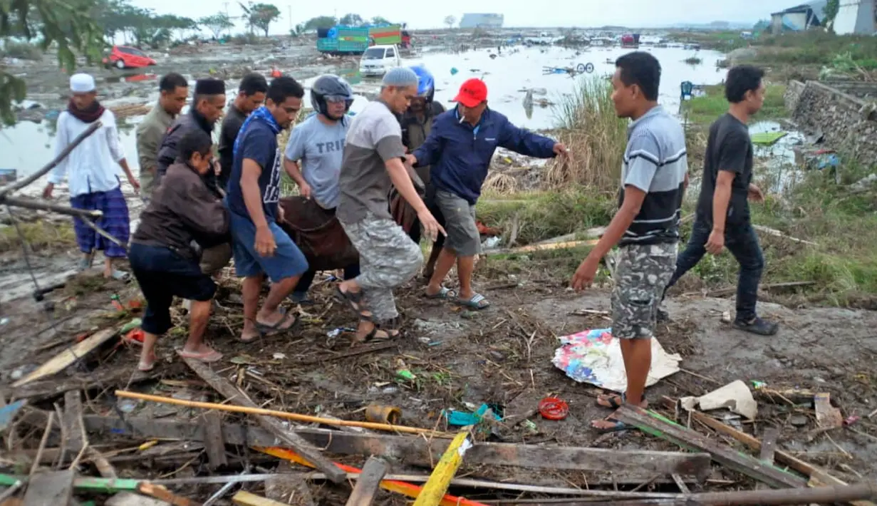 Warga mengevakuasi kantong jenazah berisi jasad korban tsunami di Palu, Sulawesi Tengah , Sabtu (29/9). Gelombang tsunami setinggi 1,5 meter yang menerjang Palu terjadi setelah gempa bumi mengguncang Palu dan Donggala. (AP Photo)