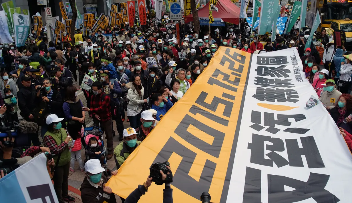 Demonstran mengunakan masker membawa spanduk raksasa saat unjuk rasa menuntut pemerintah Taiwan dalam pengurangan polusi udara di Taipei (26/12). Ratusan warga berbaris di jalan-jalan memprotes kebijakan energi pemerintah. (AFP PHOTO/Sam Yeh)