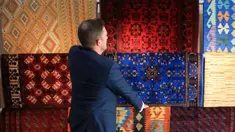Pemilik The Afghan Rug Shop James Wilthew mengatur pajangan di tokonya di Hebden Bridge, Inggris, 20 Agustus 2021. Bisnis yang menjual karpet tenunan tangan warna-warni dan kaca buatan tangan dari Afghanistan ini takut akan pemasok mereka setelah Taliban menguasai Afghanistan. (LINDSEY PARNABY/AFP)