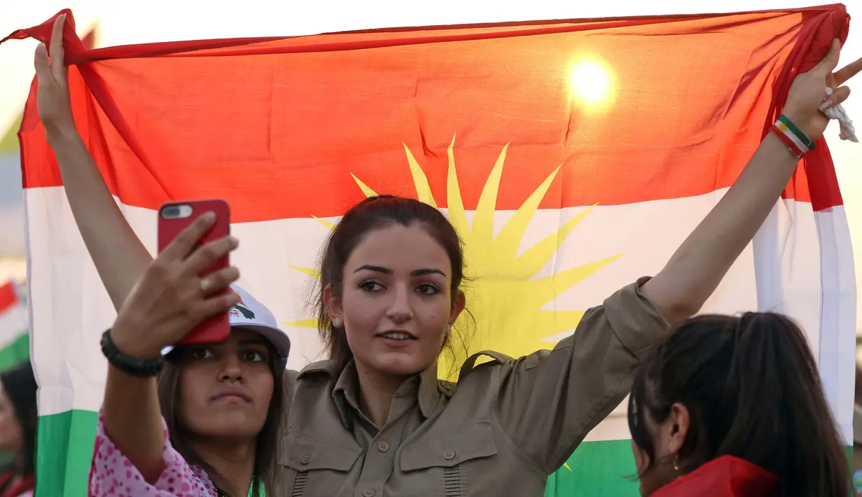 Gadis Kurdi Iran berpose mengibarkan bendera Kurdi saat mengampanyekan referendum untuk kemerdekaan di kota Bahirka, Irak Utara (21/9). (AFP Photo/Safin Hamed)