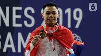 Lifter Eko Yuli menunjukkan medali emas SEA Games 2019 cabang angkat besi nomor 61 kg di Stadion Rizal Memorial, Manila, Filipina, Minggu (1/12/2019). Dirinya meraih emas dengan total angkatan 309 kg. (Bola.com/M Iqbal Ichsan)