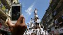Warga mengambil gambar ribuan umat Hindu yang sedang membentuk piramida manusia untuk mencapai dan memecahkan dahi-handi (pot yang terbuat dari tanah liat) pada Festival Janmashtami di Mumbai, India, 6 September 2015. (REUTERS/Danish Siddiqui)