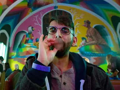 Anggota Gereja Ganja Internasional, Tushar Mallick mengisap ganja di Denver, Colorado, AS, Jumat (20/4). Aksi ini bertepatan dengan perayaan Hari Ganja Sedunia atau lebih dikenal dengan 4/20. (AFP PHOTO/Jason Connolly)