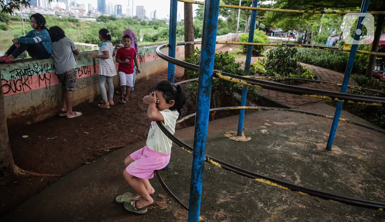 Sejumlah anak bermain di taman bermain yang terdapat di Bantaran Banjir Kanal Barat Kawasan Petamburan, Jakarta, Minggu (12/12/2021). Taman di bantaran kali kawasan padat penduduk itu menjadi sarana bermain bagi anak-anak di sekitarnya. (Liputan6.com/Faizal Fanani)