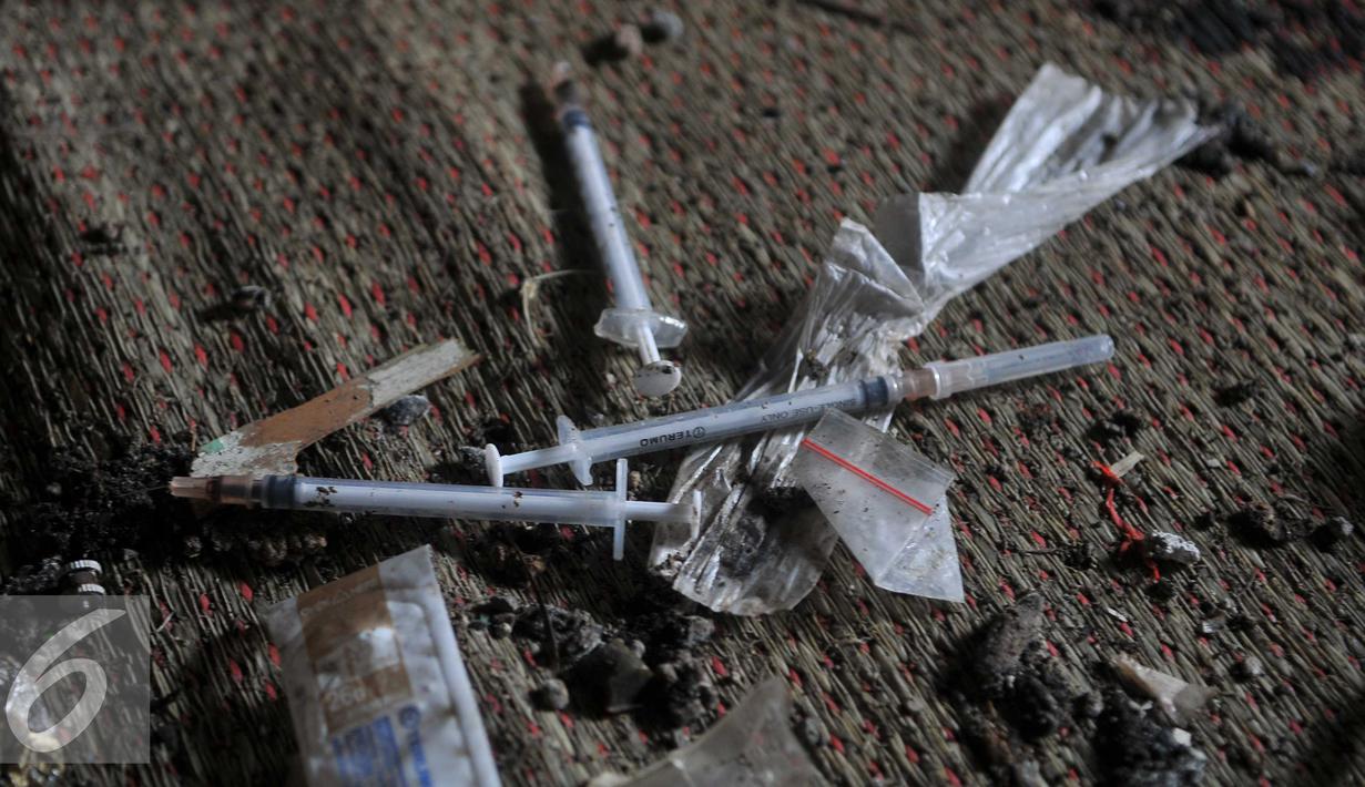 Barang bukti berupa jarum suntik dan plastik pembungkus berserakan di rumah kosong di Jalan Bendi Besar, Jakarta, Selasa (2/3). 20 orang dijaring saat kedapatan tengah mengisap sabu. (Liputan6.com/Gempur M Surya)