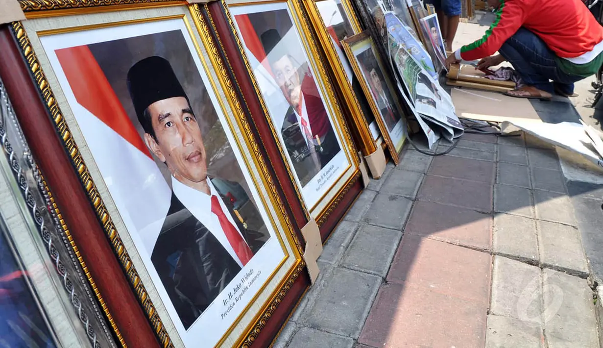 Pedagang memasukkan foto resmi kenegaraan Presiden Joko Widodo atau Jokowi dan Wakil Presiden Jusuf Kalla ke dalam pigura di Pasar Baru, Jakarta, Sabtu (25/10/2014). (Liputan6.com/Miftahul Hayat)