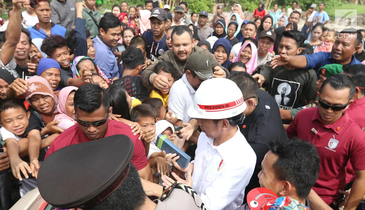 Suasana saat Presiden Joko Widodo atau Jokowi membagikan buku dan kain batik kepada warga sekitar Bandara Soetta, Tangerang, Banten, Kamis (21/6). Bagi-bagi buku tersebut merupakan rutinitas Jokowi usai blusukan. (Liputan6.com/Angga Yuniar)