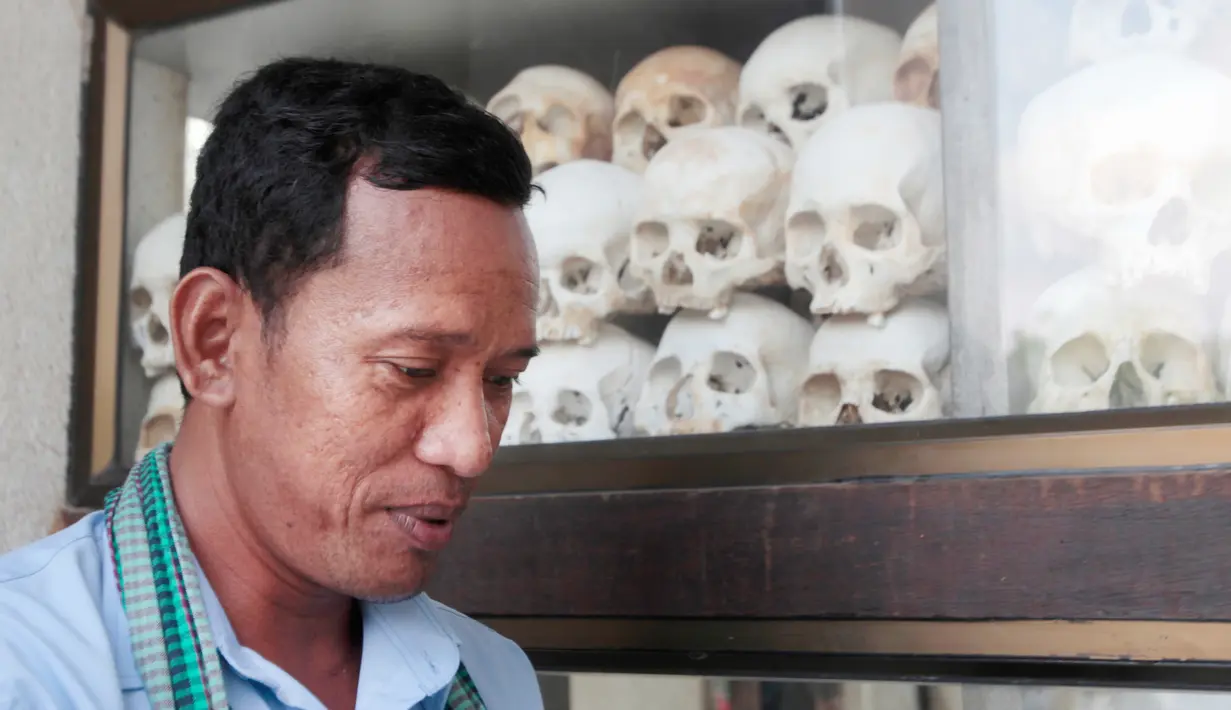 Seorang pria berdiri di depan tengkorak manusia dan tulang korban rezim Khmer Merah di Choeung Ek memorial, Kamboja (17/4). Khmer Merah adalah sayap militer Partai Komunis Kamboja yang beraliran Maois. (AP Photo/Heng Sinith)