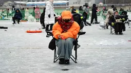 Festival Tahunan Memancing di Atas Es Hwacheon tahun 2026 secara resmi dibuka hari ini, Sabtu 10 Januari 2026, dan akan berlangsung hingga 1 Februari 2026. Tampak dalam foto, seorang wanita memancing melalui lubang di sungai yang membeku selama festival tahunan memancing di atas es, Hwacheon, Korea Selatan, pada Sabtu 10 Januari 2026. (Shin Yong-ju/AFP)