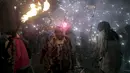 Seorang warga berpakaian seperti hantu dengan memegang tongkat kembang api selama perayaan " Correfocs ", Mallorca, Spanyol, (24/1). Orang - orang menari sambil men yalakan kembang api diantara kerumunan. (REUTERS / Enrique Calvo)