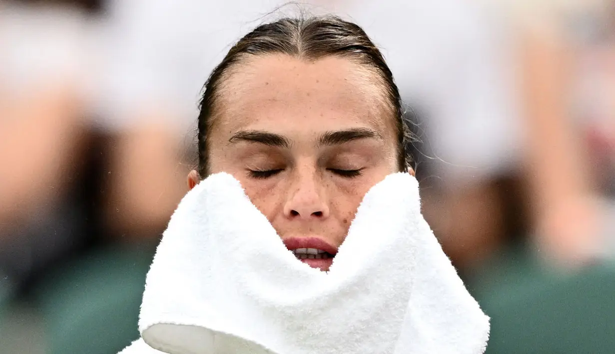 Ekspresi petenis Belarusia, Aryna Sabalenka saat menyeka wajahnya dengan handuk pada laga hari keenam tunggal putri turnamen Wimbledon 2023 melawan petenis Rusia, Anna Blinkova yang berlangsung di The All England Tennis Club, London, 8 Juli 2023. (AFP/Sebastien Bozon)
