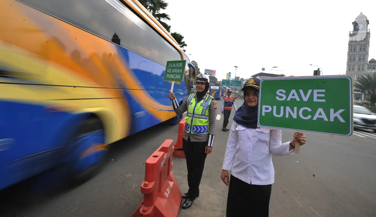 Petugas kepolisian dan Badan Pengelola Transportasi Jabodetabek (BPTJ) berdiri sambil membawa papan imbauan saat uji coba sistem kanalisasi 2-1 Jalur Puncak di kawasan Gadog, Bogor, Jawa Barat, Minggu (27/10/2019). (merdeka.com/Arie Basuki)