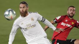 Bek Real Madrid, Sergio Ramos, berebut bola dengan pemain Real Mallorca, Dani Rodriguez, pada laga La Liga di Stadion Alfredo Di Stefano, Kamis (25/6/2020). Real Madrid menang 2-0 atas Real Mallorca. (AP/Bernat Armangue)