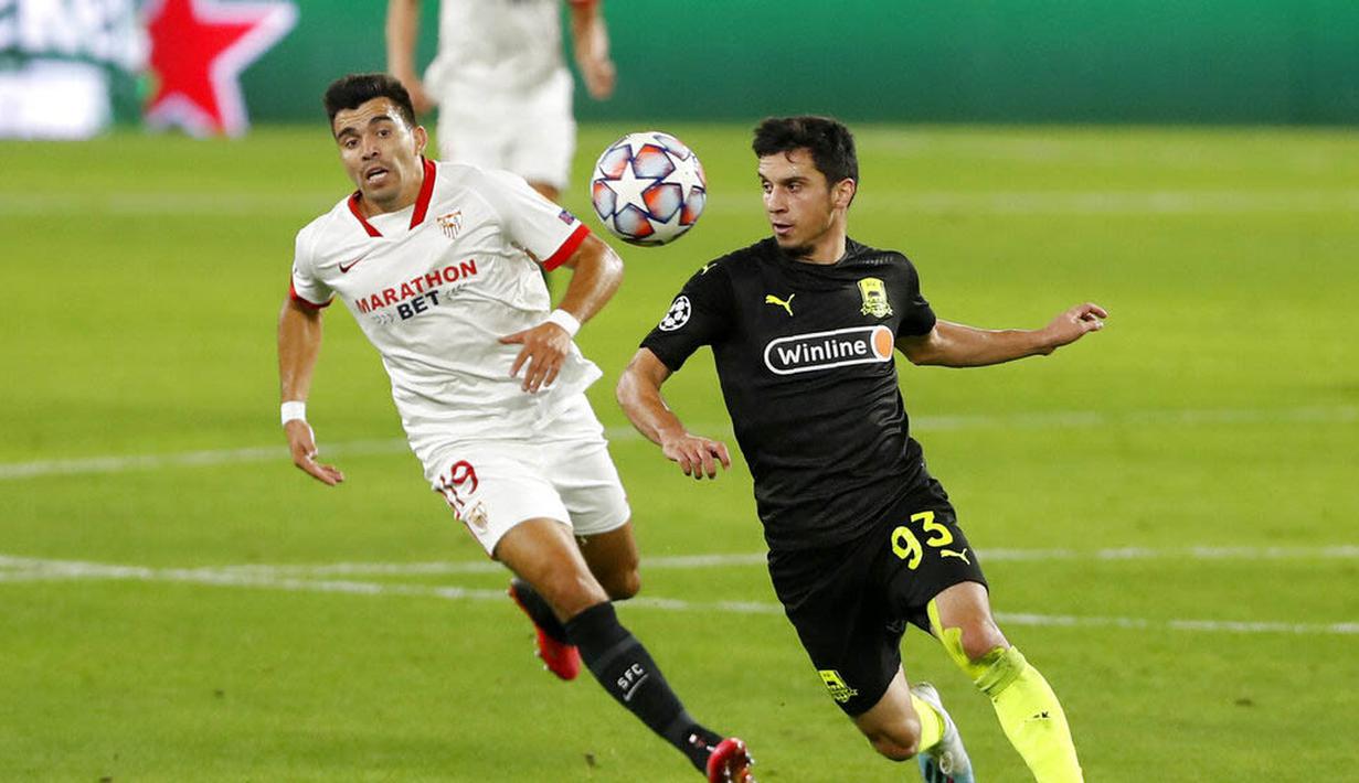 Kiper Krasnodar, Magomed-Shapi Suleymanov, berebut bola dengan pemain Sevilla, Marcos Acuna, pada laga Liga Champions di Stadion Ramon Sanchez Pijuan, Kamis (5/11/2020). Sevilla menang dengan skor 3-2. (AP Photo/Miguel Morenatti)