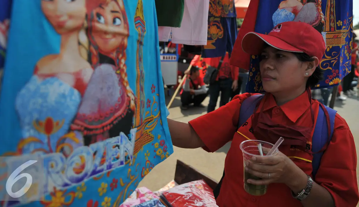 Buruh memilih pakaian saat demo memperingati hari lahirnya organisasi buruh internasional World Federation of Trade Unions (WFTU) di Jakarta (3/10/2015).  Sejumlah PKL memanfaatkan demo buruh untuk meraup sedikit keuntungan. (Liputan6.com/Gempur M Surya)