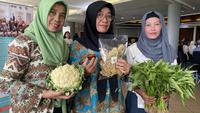Nunung (kiri), Ivon (tengah), dan Nengsih (kanan), memegang sayur hasil panen dari kebun mereka dalam acara pameran Bibit ka Jati bagian dari kegiatan Urban Features di Bumi Sangkuriang, Bandung, Selasa, 10 Februari 2026. (Liputan6.com/Dikdik Ripaldi)
