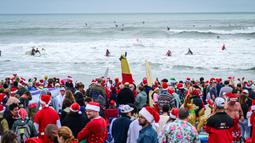 Pengunjung memadati acara Surfing Santa yang berlangsung di Pantai Cocoa, Florida, Amerika Serikat, Selasa (24/12/2024) waktu setempat. (AFP/Giorgio Viera)
