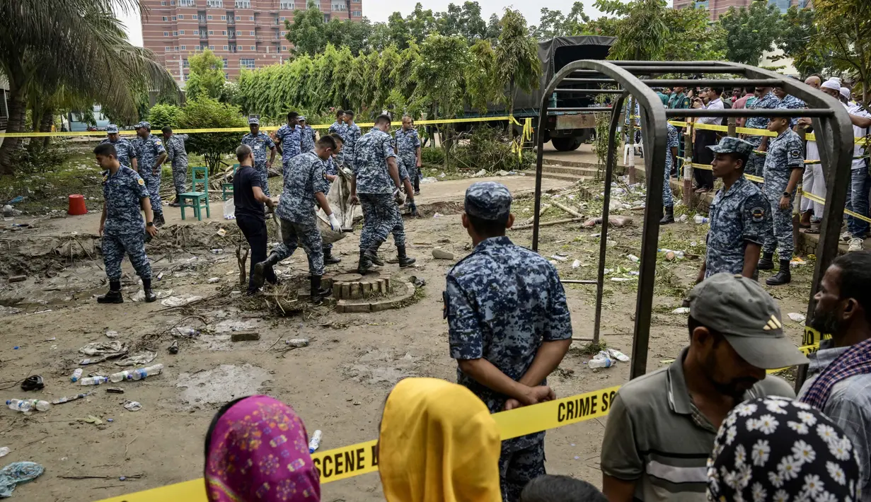 Warga berkumpul dan menyaksikan aktivitas sejumlah personel Angkatan Udara Bangladesh membersihkan puing-puing saat memeriksa lokasi jatuhnya pesawat latih milik Angkatan Udara Bangladesh yang menimpa kompleks sekolah di Dhaka, 22 Juli 2025. (MUNIR UZ ZAMAN/AFP)
