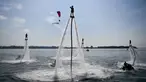 Seorang flyboarder (tengah) memberi hormat saat gladi bersih sehari jelang upacara pembukaan latihan angkatan laut multilateral Komodo 2025 di pelabuhan Benoa, Denpasar, Bali, pada 15 Februari 2025. (SONNY TUMBELAKA/AFP)