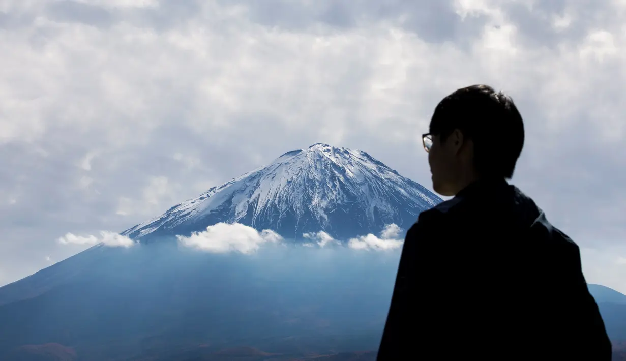 Turis melihat Gunung Fuji dari Fujikawaguchiko, Prefektur Yamanashi (1/11). Gunung Fuji adalah simbol Jepang yang terkenal dan sering digambarkan dalam karya seni dan foto-foto, serta dikunjungi pendaki gunung maupun wisatawan. (AFP Photo/Behrouz Mehri)
