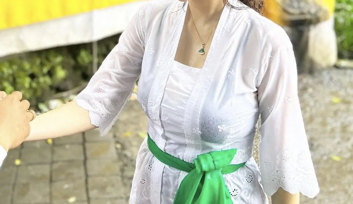 Dalam akun Instagramnya, Aura Kasih membagikan potret sedang melalukan prosesi melukat. Ia tampil dengan kebaya kutu baru putih serta kalung yang menghiasi lehernya. (@aurakasih)