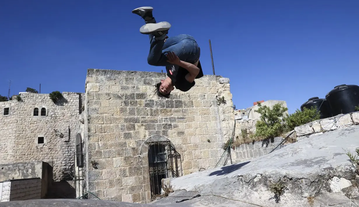 Pemuda Palestina Usaid Abu Khalaf berlatih parkour di atas atap dan tangga rumah batu tradisional di Kota Hebron, Tepi Barat, Sabtu (5/6/2021). (HAZEM BADER/AFP)