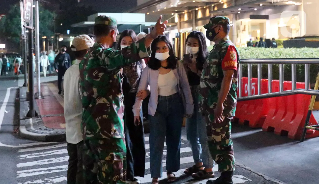 Tentara melakukan pembubaran terhadap warga yang berkerumun di kawasan Bundaran HI, Jakarta, Jumat (31/12/2021). Untuk mencegah penyebaran COVID-19, petugas gabungan melakukan pembubaran aktivitas warga di malam Tahun Baru. (Liputan6.com/Angga Yuniar)
