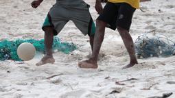 Kaki-kaki pemuda pemuda desa berebut bola saat bermain bola dekat pantai di Desa Matwaer, Kei Kecil, Maluku (25/12/2017).  Bermain bola di pasir menjadi daya tarik tersendiri bagi anak-anak dan pemuda desa. (Bola.com/Nick Hanoatubun)