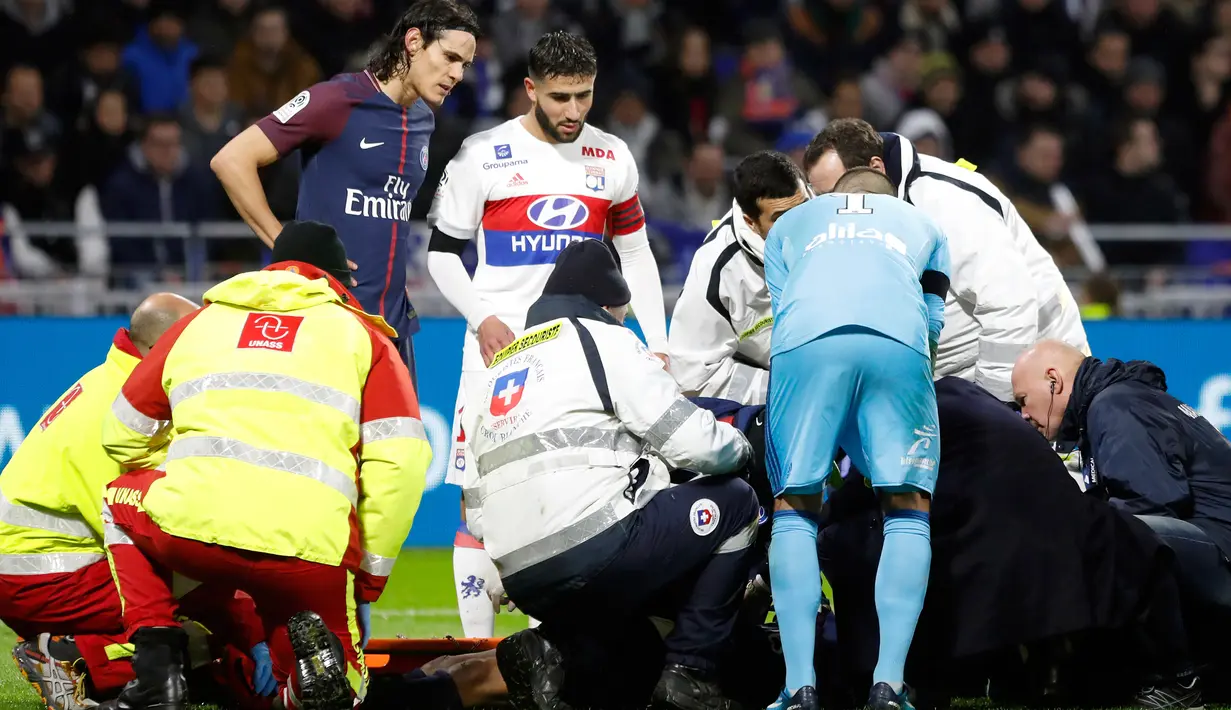 Petugas medis memberikan pertolongan kepada pemain PSG, Kylian Mbappe setelah berbenturan dengan kiper Olympique Lyon, Anthony Lopes dalam lanjutan Ligue 1 di Groupama Stadium, Senin (22/1). Benturan itu membuat Mbappe cedera. (AP/Laurent Cipriani)