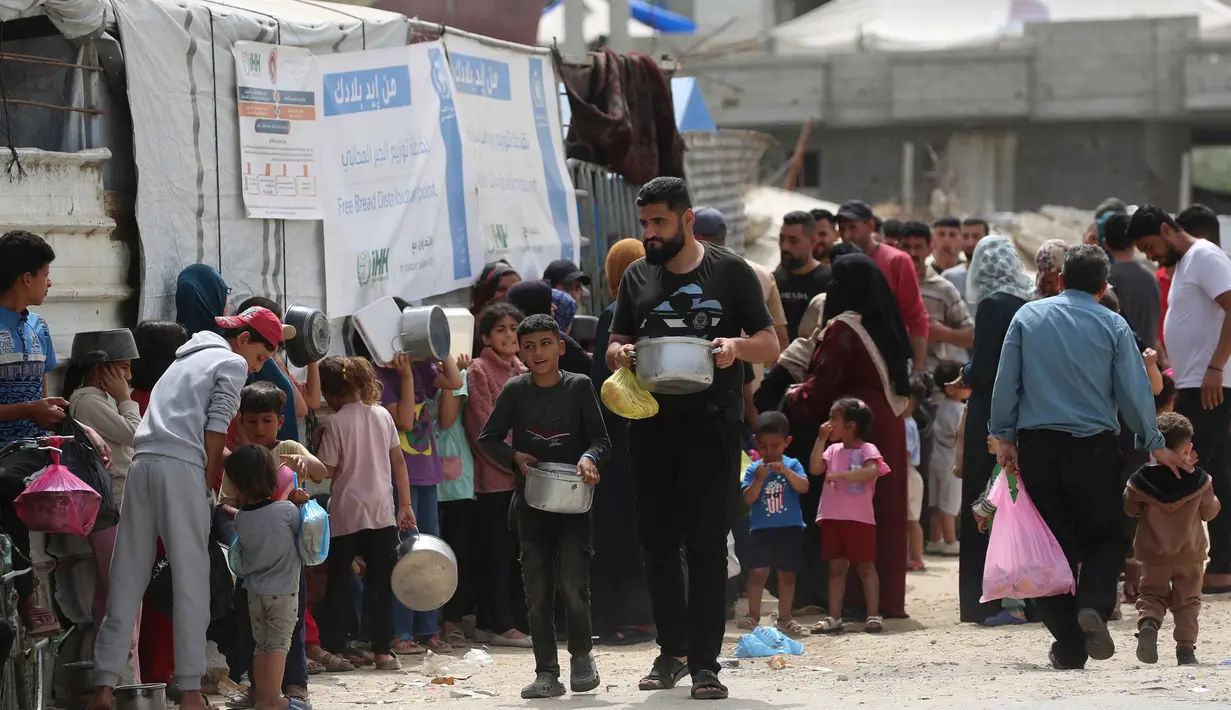 Keluarga-keluarga Palestina yang mengungsi sambil memegang wadah kosong menunggu giliran untuk mengambil makanan dari dapur amal, di kamp pengungsi Bureij, Jalur Gaza Tengah pada Senin 18 Mei 2026. (Eyad Baba/AFP)