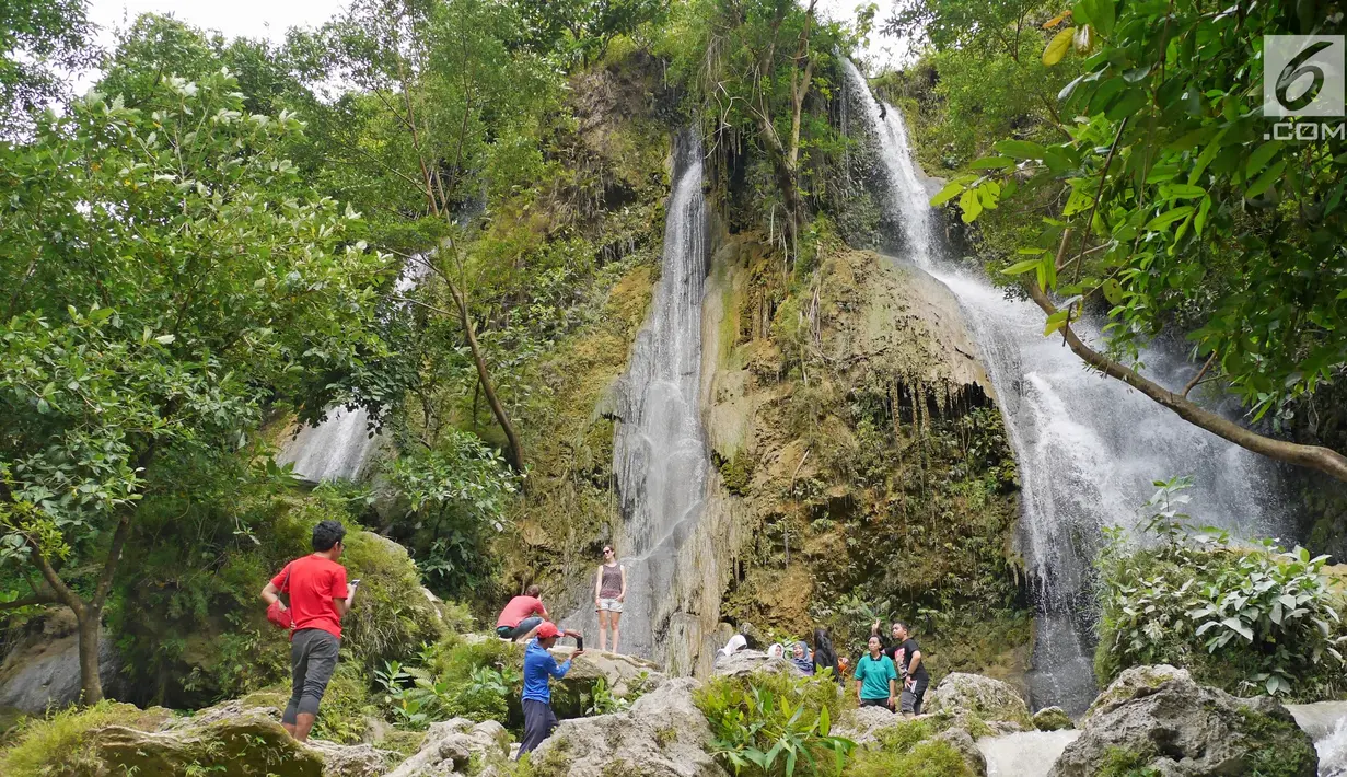Sejumlah wisatawan menikmati air terjun dengan berfoto di Air Terjun Sri Gethuk, Kabupaten Gunungkidul, Yogyakarta, Sabtu (11/11). Wisatawan harus menempuh perjalanan melintasi Sungai Oya sepanjang 400 meter. (Liputan6.com/Herman Zakharia)