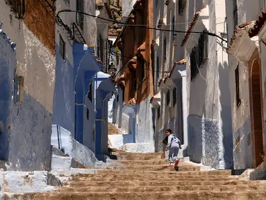 Seorang anak berjalan disebuah anak tangga di Kota Chefchaouen, Maroko, Minggu (1/5). Chefchaouen baru-baru ini dinobatkan sebagai kota terindah keenam dari 50 kota di dunia menurut Conde Nast Traveler. (FADEL SENNA / AFP)