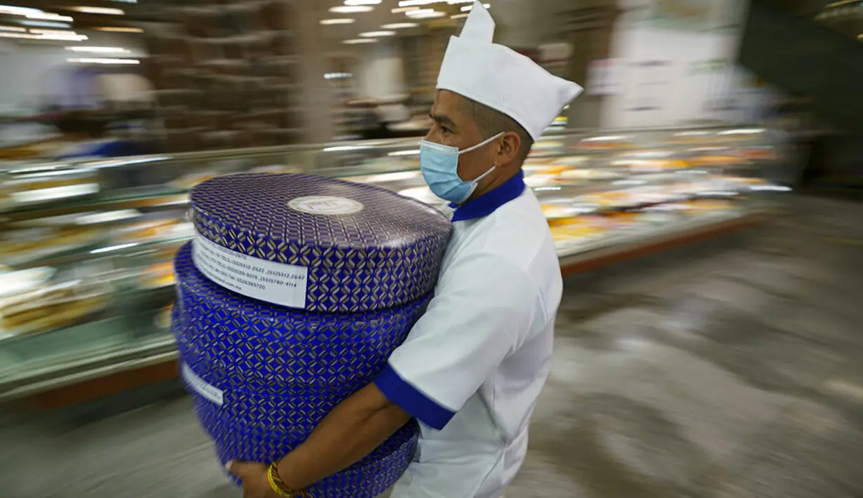 Seorang pekerja toko roti membawa kue tradisional Rosca de Reyes untuk pembeli sehari sebelum Epiphany atau Hari Tiga Raja di Mexico City, Meksiko, 5 Januari 2022. (AP Photo/Fernando Llano)