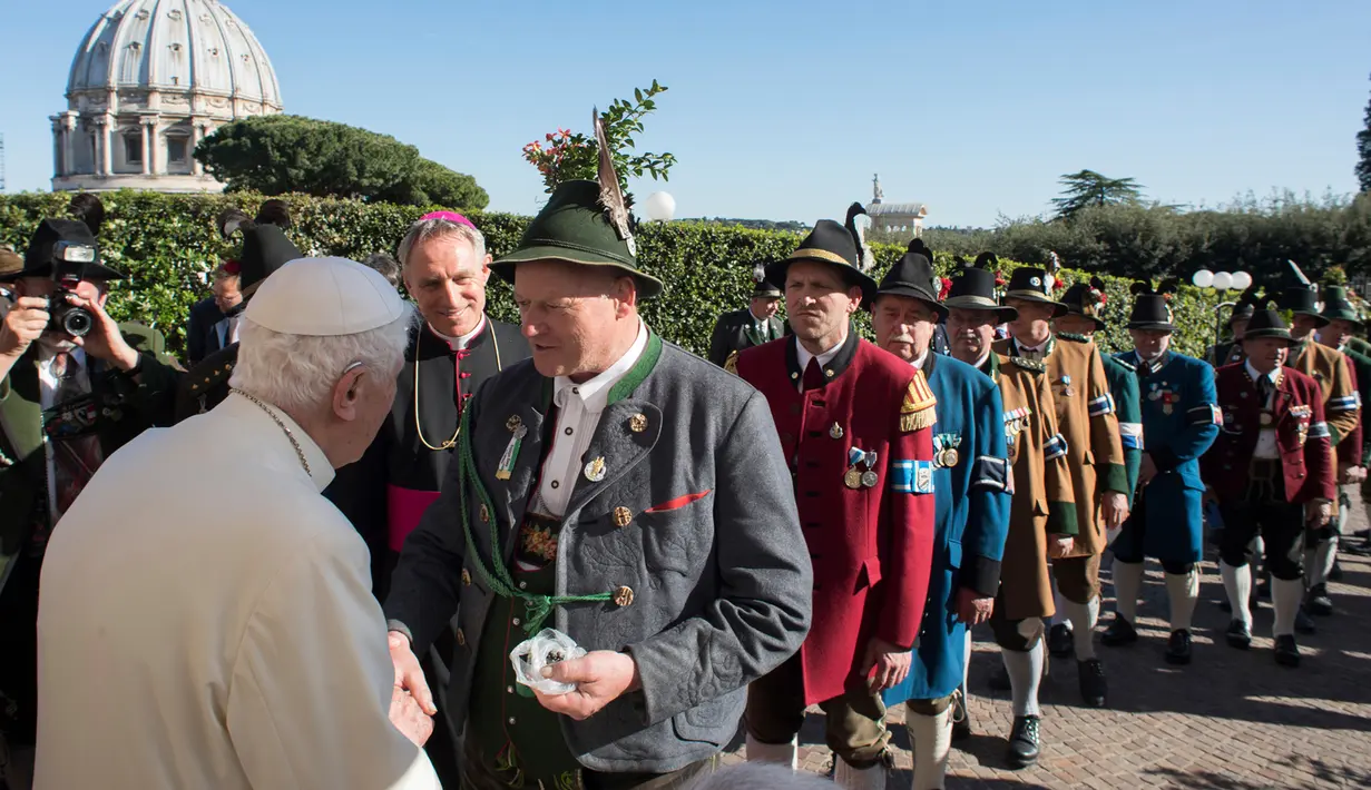 Paus Emeritus Benediktus XVI bersalaman dengan para delegasi dari Bavaria saat ulang tahunnya yang ke-90 di Vatikan (17/4). Perayaan ulang tahun Paus Benediktus digelar pada hari Senin dengan tradisi Bavarian. (L'Osservatore Romano/Pool Photo via AP)