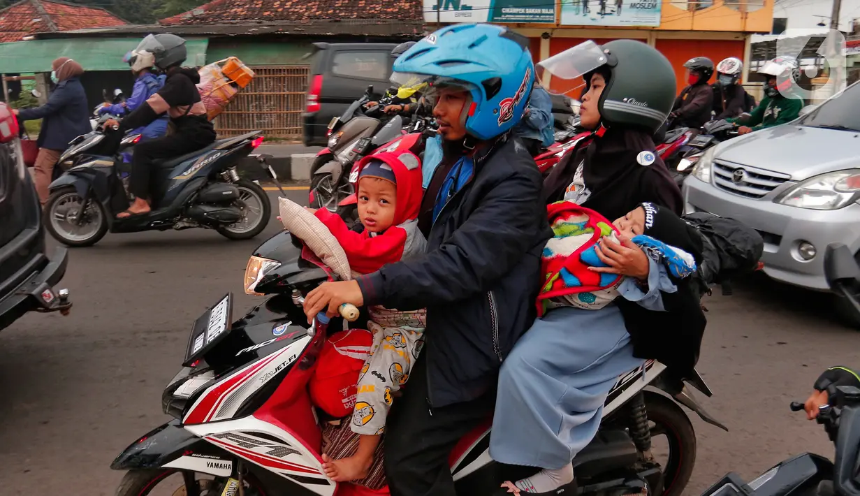 Pemudik sepeda motor saat berboncengan dengan anak-anak melintasi Simpang Jomin, Jawa Barat, Rabu (19/4/2023). (Liputan6.com/Angga Yuniar)
