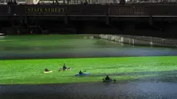 Orang-orang bermain kayak di sepanjang Sungai Chicago yang berwarna hijau jelang Hari Santo Patrick di Chicago, Amerika Serikat, Sabtu (13/3/2021). Kegiatan mewarnai Sungai Chicago dalam rangka memperingati Hari Santo Patrick sudah berlangsung selama 40 tahun. (Pat Nabong/Chicago Sun-Times via AP)