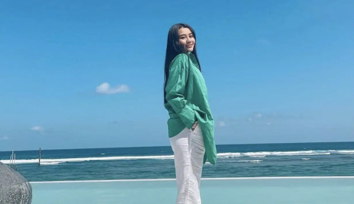 Bukan bikini, Aaliyah mengenakan kemeja oversize hijau dipadukan celana putih panjangnya. Dengan rambut yang terurai.  [@aaliya.massaid]