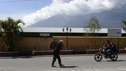 Warga beraktivitas saat Gunung Fuego mengeluarkan abu tebal yang terlihat dari kota Antigua, Sacatepequez, 45 km tenggara Kota Guatemala (1/2). (AFP Photo/Johan Ordonez)