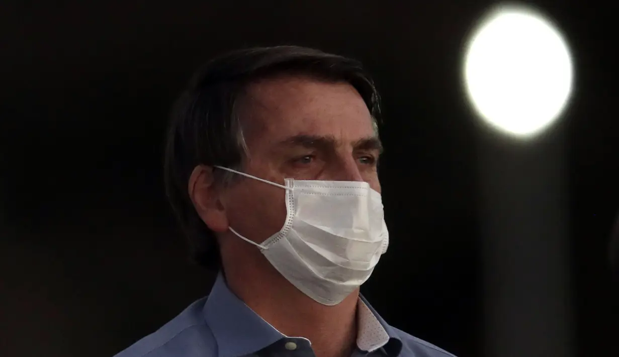 Presiden Brasil Jair Bolsonaro mengenakan masker saat upacara retret bendera di luar Istana Alvorada, Brasilia, Brasil, Jumat (24/7/2020). Jair Bolsonaro dinyatakan positif terinfeksi COVID-19 pada 7 Juli lalu. (AP Photo/Eraldo Peres)
