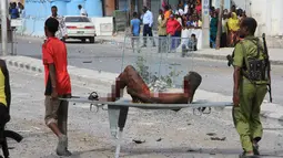 Seorang pria yang terluka dalam serangan bom mobil bunuh diri ditandu oleh petugas Palang Merah Somalia di Mogadishu, Somalia, Rabu (25/1).  Setidaknya 13 orang dilaporkan tewas dan puluhan lainnya terluka dalam kejadian ini. (AP Photo)