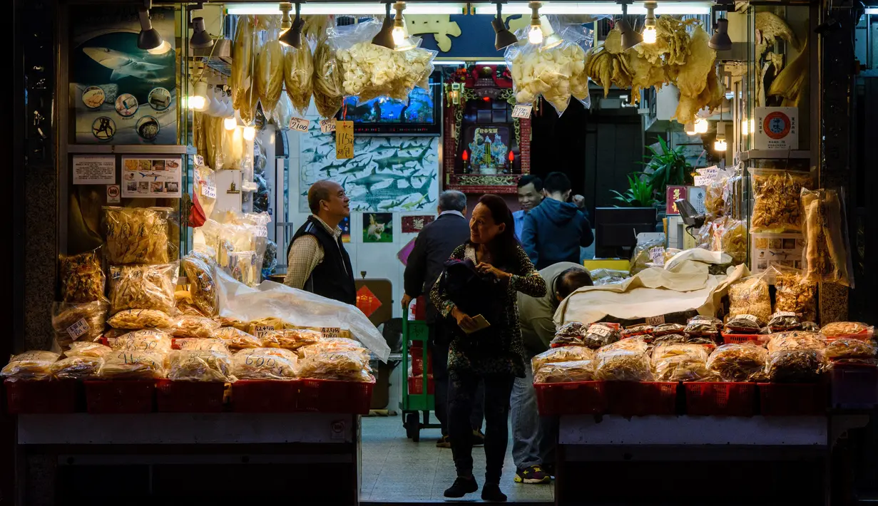 Pedagang sirip ikan hiu melayani pembeli di tokonya di Hong Kong (6/3). Namun budaya mengkonsumsi sirip ikan hiu di Hong Kong makin meluas dan banyak ditemukan dalam menu di restoran seafood di kota tersebut. (AFP/Anthony Wallace)