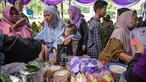 Masyarakat menerima barang-barang gratis seperti pakaian, bahan makanan pokok, dan perlengkapan rumah tangga yang disediakan oleh Asosiasi Organisasi Wanita (GOW) dan pemerintah daerah selama kegiatan aksi sosial tahunan di bulan Ramadan, Surabaya pada Senin 2 Maret 2026. Bersama Pemerintah Kota Surabaya, Jawa Timur, Gabungan Organisasi Wanita (GOW) aksi sosial tahunan, berupa peendistribusian berbagai barang bantuan kepada warga yang membutuhkan. (JUNI KRISWANTO/AFP)