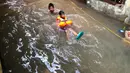 Anak-anak bermain di tengah banjir yang merendam kawasan Kebon Pala, Jakarta Timur, Selasa (25/2/2020). Akibat banjir yang tak kunjung surut, aktivitas warga di kawasan tersebut menjadi terganggu, terlebih dengan adanya pemadaman listrik. (Liputan6.com/Immanuel Antonius)