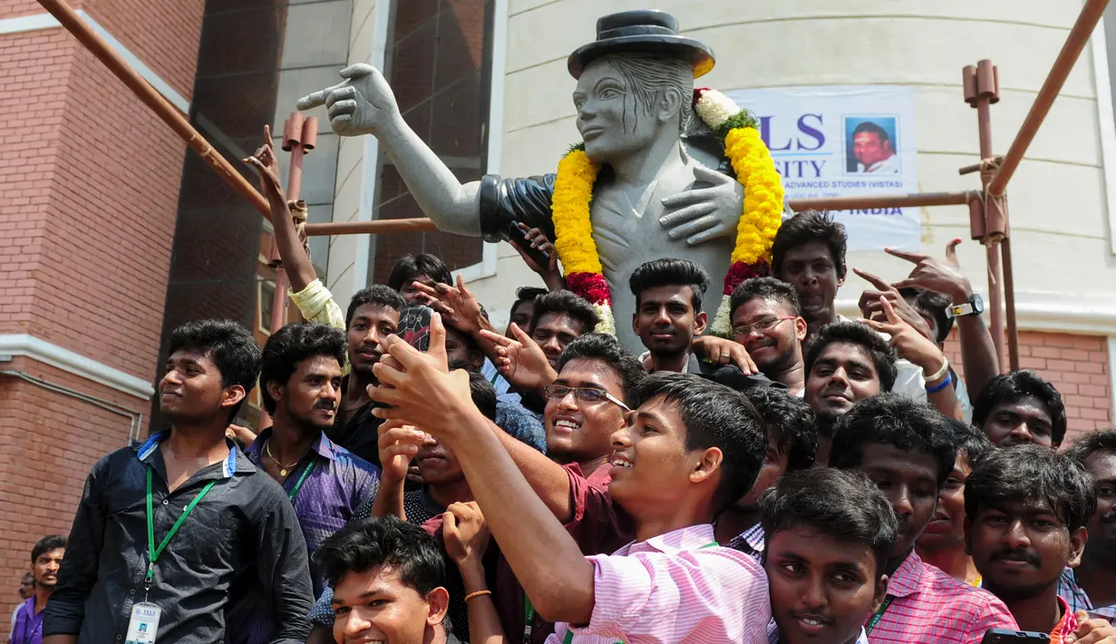 Sejumlah pelajar mengambil foto bersama patung bintang pop AS Michael Jackson di Chennai, India, Kamis (7/4). Patung Ini bergaya khas tarian dari Michael Jackson. (Arun Sankar/AFP)